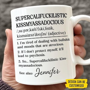 May include: White ceramic mug featuring the phrase "SUPERCALIFUCKILISTIC KISSMYASSADOCIOUS" and its definition. The mug also includes the name "Jennifer" and the phrase "DESIGN CAN BE CUSTOMISED".