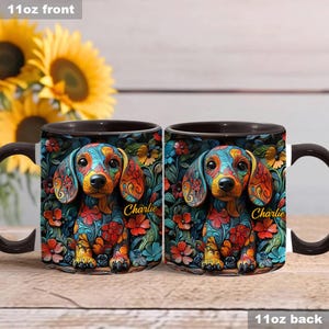 Puede incluir: Dos tazas de cer&aacute;mica negra de 11 onzas con un dise&ntilde;o floral colorido y un perro salchicha en el centro. El perro lleva un patr&oacute;n floral y el nombre "Charlie" est&aacute; escrito en cada taza.