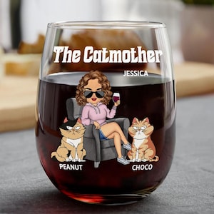 May include: A personalized wine glass with the text "The Catmother Jessica" and a cartoon illustration of a woman with two cats. The cats are named "Peanut" and "Choco".