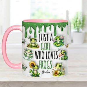May include: A white ceramic mug with a pink rim and green dripping paint design. It features a cartoon frog design with the text "Just a girl who loves frogs" and a personalized name "Sophia".