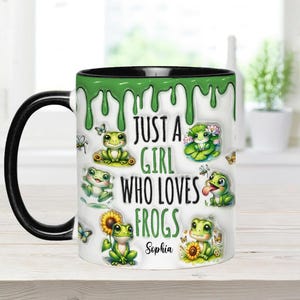 May include: A white ceramic mug with a black handle and a green dripping design. The mug features a variety of cartoon frogs and the text "Just a girl who loves frogs" with the name "Sophia" at the bottom.