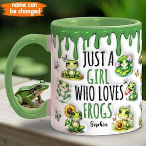 May include: A green and white ceramic mug with a dripping green glaze. The mug features a cartoon frog design and the text "Just a girl who loves frogs" with a personalized name.