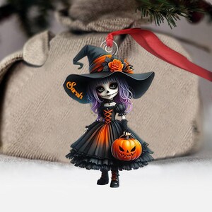 May include: A personalized Halloween ornament featuring a witch with a black and orange dress, a black hat, and a pumpkin. The witch's name, "Sarah", is written on the hat.