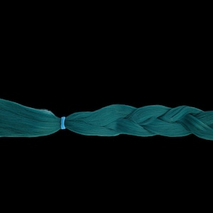Peut inclure: Une tresse de cheveux de couleur teal, fixée avec un élastique bleu clair. La tresse est d'une teinte vibrante de teal, avec une texture lisse et brillante. Le fond est noir uni.