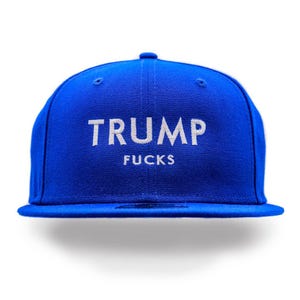 Puede incluir: Una gorra de b&eacute;isbol azul con bordado blanco que dice "TRUMP FUCKS".