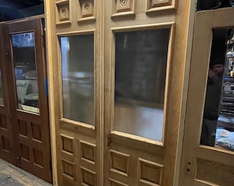 May include: A pair of antique wooden doors with glass panels and intricate carvings. The doors are stained a light brown color and have a distressed finish.