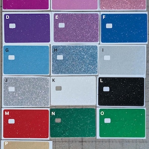 May include: A collection of rectangular glitter-covered stickers in various colors, including pink, purple, blue, silver, red, and green. Each sticker has a white rectangular cutout. The stickers are arranged in a grid, showcasing a range of hues and textures.