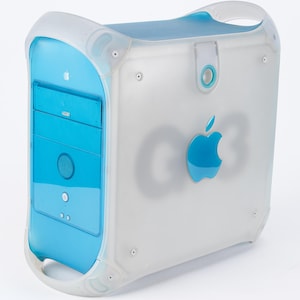 May include: A translucent white and blue Apple G3 computer. The computer has a light blue front panel with a speaker and drive bays. The Apple logo is visible on the side, along with the text "G3". The computer has a handle on top.