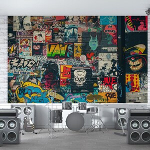 May include: A music studio setup featuring a graffiti-covered wall backdrop with posters and artwork. The room includes a drum set, guitar, amplifiers, and speakers, creating a rock and roll theme.
