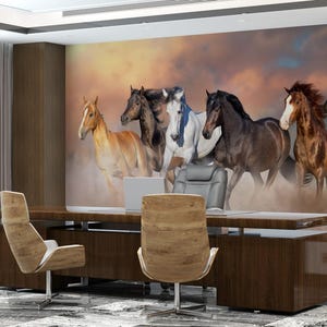 May include: A wall mural featuring a group of seven horses running through a field. The horses are all different colors, including brown, white, and black. The background is a sunset sky with clouds.