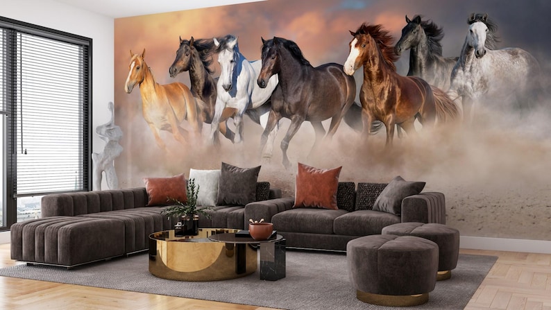 May include: A group of seven horses running through a dusty field. The horses are all different colors, including brown, white, and black. The horses are running towards the camera, and the dust is kicking up behind them.