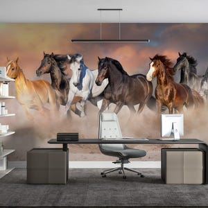 May include: A wall mural featuring a group of seven horses running through a field. The horses are brown, white, and black, and they are running in a line. The background is a blurry image of a field with a sunset in the distance.