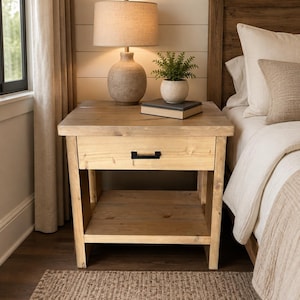 May include: A light brown wooden nightstand featuring a single drawer with a matte black rectangular handle and an open lower shelf. The nightstand is constructed from natural wood with visible grain patterns and a sturdy four-legged frame design.