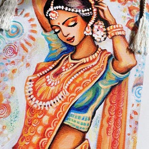 May include: A colorful painting of a woman in traditional Indian attire. The woman is adorned with jewelry and a headpiece, with her eyes closed. The artwork features vibrant orange, blue, and white hues, with decorative tassels on the sides.