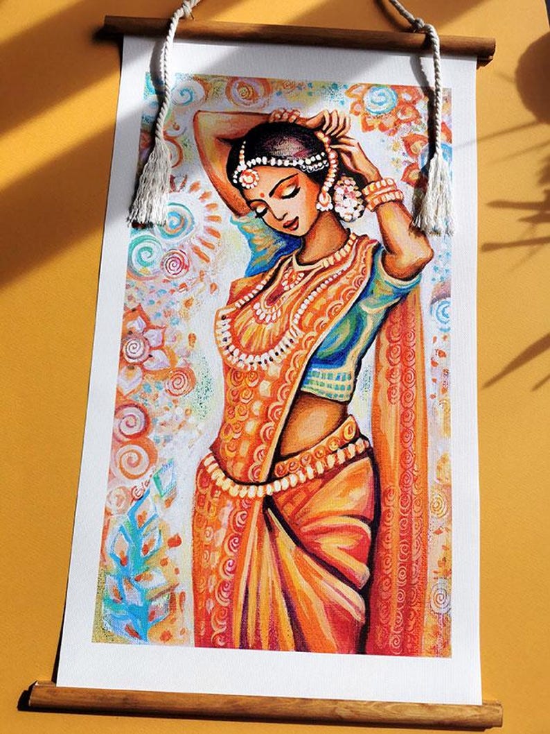 May include: A watercolor print of a woman in traditional Indian attire, featuring an orange sari with intricate patterns and jewelry. The artwork is displayed on a scroll with wooden rods and a hanging rope.