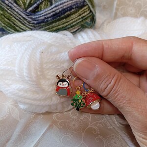 May include: Three Christmas-themed stitch markers with a penguin, a Christmas tree, and a bell. The markers are gold-toned with colorful enamel details.