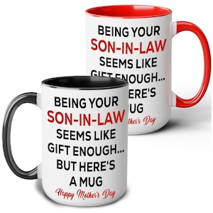 May include: Two white ceramic mugs with black and red accents. The mugs have the text "BEING YOUR SON-IN-LAW SEEMS LIKE GIFT ENOUGH... BUT HERE'S A MUG Happy Mother's Day" printed on them in black and red.