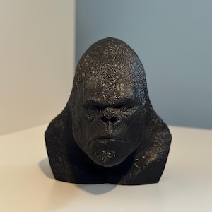 May include: A black 3D printed bust of a gorilla with a serious expression.
