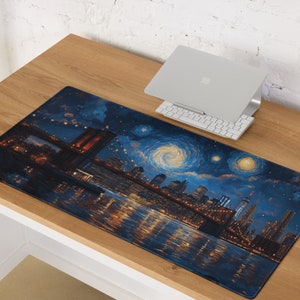 K&ouml;nnte beinhalten: Eine blaue und schwarze Schreibtischunterlage mit einem Stadtbild- und Br&uuml;ckenmotiv. Das Design erinnert an ein ber&uuml;hmtes Gem&auml;lde einer sternenklaren Nacht. Die Unterlage liegt auf einem Holztisch mit einem Laptop und einer Tastatur.