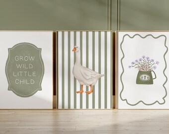 May include: Three framed art prints with gold frames. The left print has the text "GROW WILD LITTLE CHILD" in a green, decorative frame. The center print features a goose on a striped background. The right print shows a vase of purple flowers.