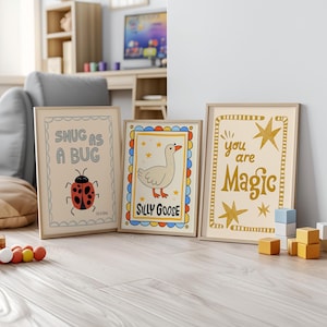 May include: Three framed art prints with whimsical designs. One says "Snug as a Bug" with a ladybug illustration. Another says "Silly Goose" with a goose illustration. The third says "You are Magic" with star accents.