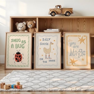 May include: Three framed art prints with whimsical designs and text. One says "Snug as a Bug" with a ladybug illustration. Another says "Silly Goose on the Loose" with a goose. The third says "You are Magic".