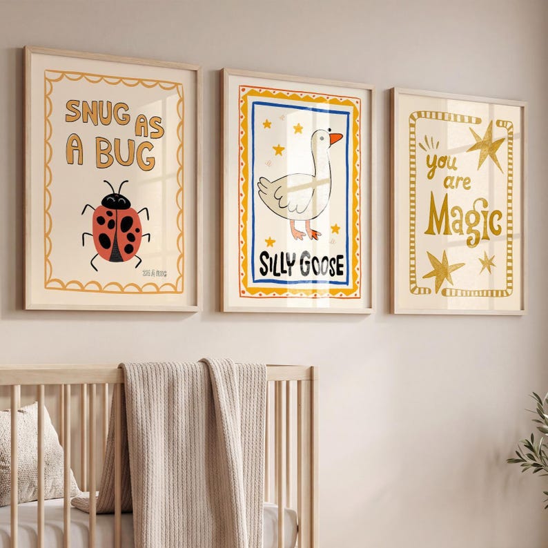 May include: Three framed art prints with whimsical illustrations. One print says "SNUG AS A BUG" with a ladybug. Another says "SILLY GOOSE" with a goose. The third says "you are Magic" with stars. The prints are in light wood frames.