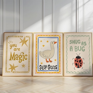 May include: Three framed art prints with whimsical illustrations. One says "you are Magic" with gold stars. Another features a cartoon goose and the words "Silly Goose." The third says "Snug as a Bug" with a ladybug.