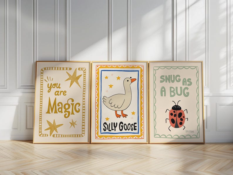 May include: Three framed art prints with whimsical illustrations. One says "you are Magic" with gold stars. Another features a cartoon goose and the words "Silly Goose." The third says "Snug as a Bug" with a ladybug.