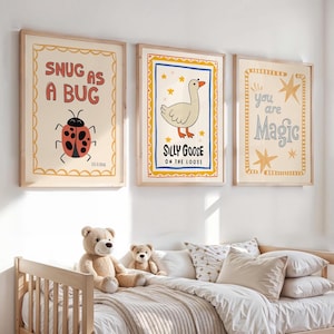May include: Three framed art prints with whimsical illustrations. One says "SNUG AS A BUG" with a ladybug, another says "SILLY GOOSE ON THE LOOSE" with a goose, and the last says "you are Magic". The prints are in a child's bedroom.