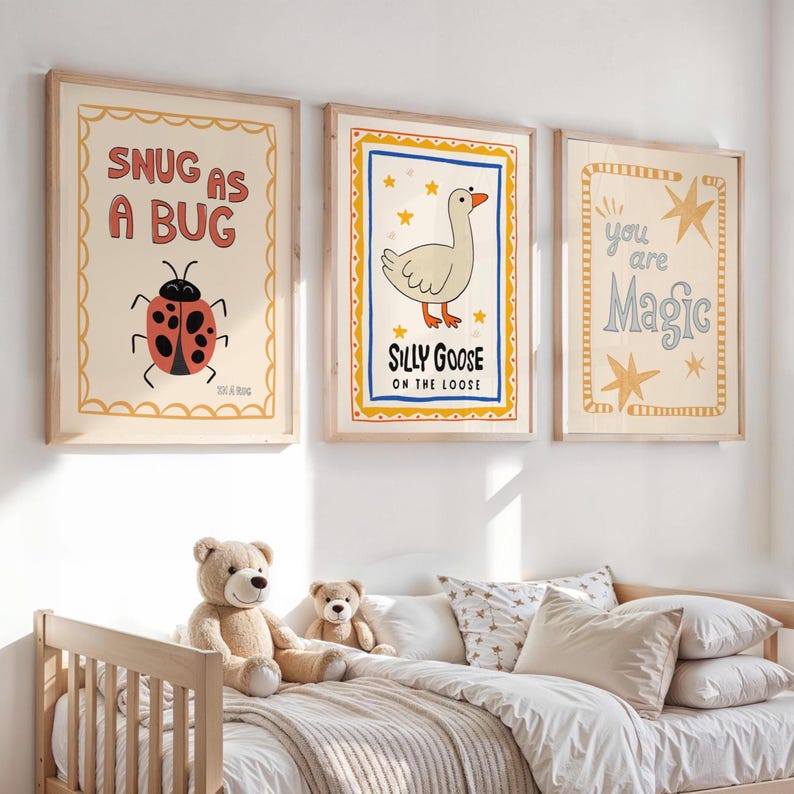 May include: Three framed art prints with whimsical illustrations. One says "SNUG AS A BUG" with a ladybug, another says "SILLY GOOSE ON THE LOOSE" with a goose, and the last says "you are Magic". The prints are in a child's bedroom.