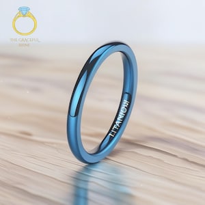 May include: A simple blue titanium ring with a polished finish. The ring is engraved with the word "TITANIUM".