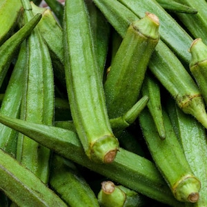 May include: Close-up of fresh okra pods, showcasing their vibrant green color and ribbed texture. The image highlights the elongated shape and the small, brown stem ends of the okra. A healthy and natural food.