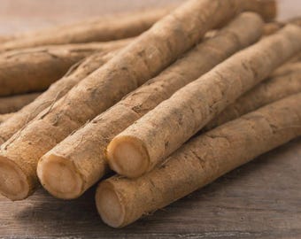 May include: A collection of long, cylindrical burdock roots with a light brown, textured, and fibrous outer skin. The roots are arranged in a pile, showcasing their straight, elongated shape and the pale, circular cross-sections at the cut ends.