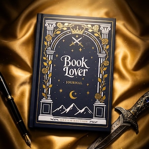 Könnte beinhalten: Ein dunkelblaues Hardcover-Notizbuch mit dem Titel Book Lover Journal Dream Edition, verziert mit goldenen Illustrationen von Torbögen, Rosen, gekreuzten Schwertern, einer Mondsichel, Sternen und Bergen, neben einem Füllfederhalter und einem Dolch.