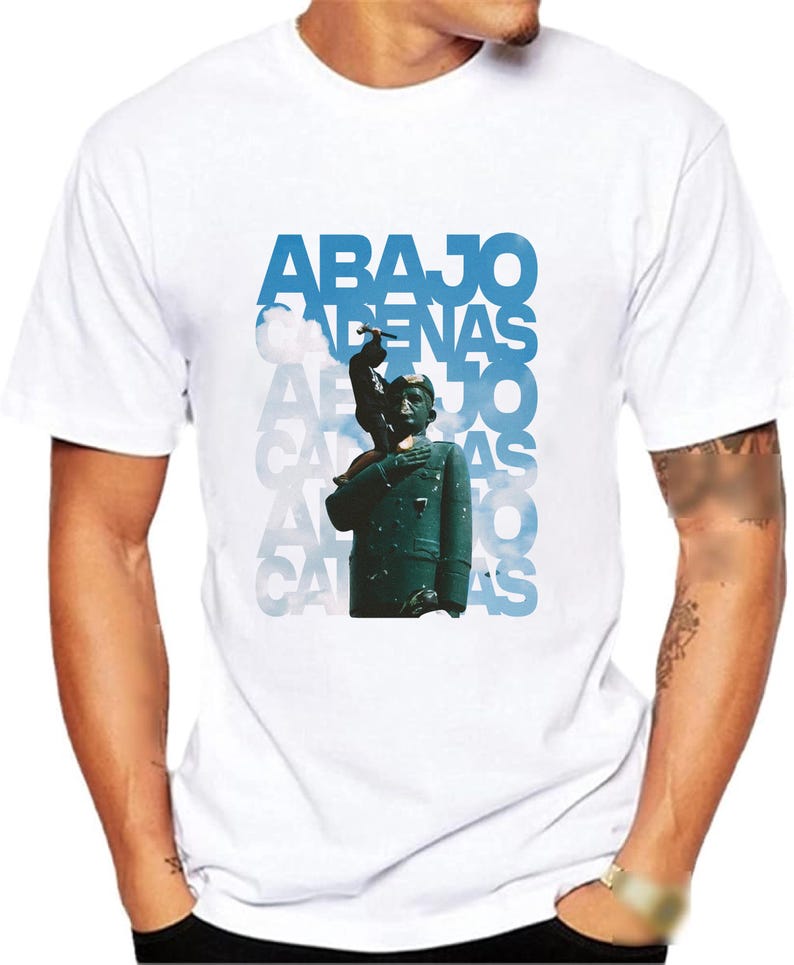 May include: White t-shirt with a blue and white graphic print of a person standing on a cloud with the text "ABAJO CADENAS" repeated multiple times.