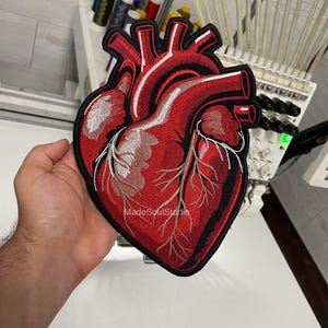 May include: Embroidered patch with a detailed anatomical heart design in red, black, and white. The patch has a black border and the text "MadeSoulStudio".