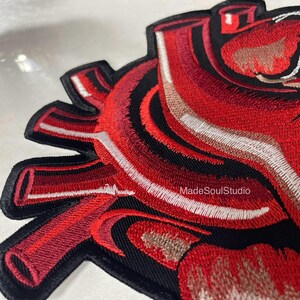 May include: Embroidered patch with a detailed anatomical heart design. The patch features shades of red, black, and white, with intricate stitching. The text "MadeSoulStudio" is visible on the patch.