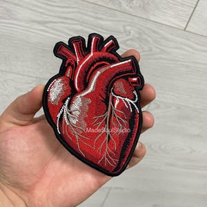 May include: Embroidered patch featuring a detailed anatomical heart design in shades of red, with white and black accents. The patch has a black border and the text "Made Soul Studio".