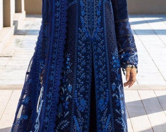 May include: A navy blue embroidered dress with detailed floral patterns. The dress has long sleeves and a sheer overlay. The design includes a high neckline and lace detailing. The dress is worn with white heels.