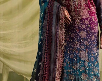 Puede incluir: Vestido de manga larga en tonos burdeos, verde azulado y marino, adornado con intrincados bordados dorados y motivos florales. El vestido presenta un diseño fluido con un chal a juego, ideal para ocasiones especiales.