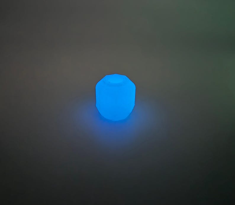 May include: A glowing, blue, geometric-shaped light fixture. The light emits a soft, ambient glow, creating a modern and inviting atmosphere. The fixture's design is simple yet eye-catching, perfect for adding a touch of color.