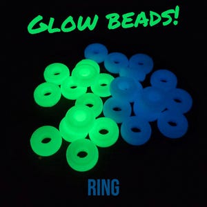 May include: A close-up of a pile of glow-in-the-dark beads in green and blue. The beads are arranged in a ring shape and the text "GLOW BEADS!" is written above the beads. The text "RING" is written below the beads.