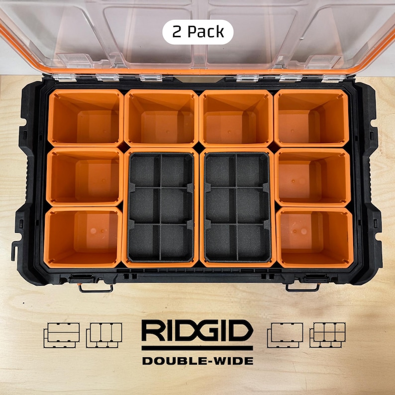 May include: A black and orange double-wide storage container with a clear lid. The container has multiple orange compartments and two black compartments. The text "2 Pack" is visible on the lid. The brand name "RIDGID" and the text "DOUBLE-WIDE" are printed on the container.