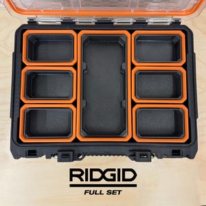 May include: Black and orange RIDGID Full Set tool organizer with a clear lid. The interior features multiple compartments of varying sizes. The organizer is designed for tool storage and organization.