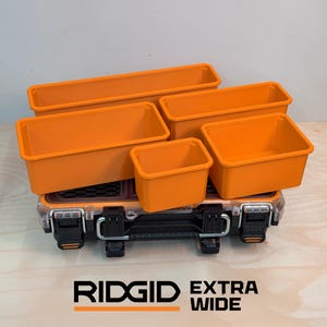 Puede incluir: Un conjunto de cinco contenedores de almacenamiento rectangulares de color naranja de varios tamaños dispuestos sobre una caja de herramientas Ridgid Extra Wide negra y transparente con cierres metálicos. Los contenedores tienen paredes lisas.