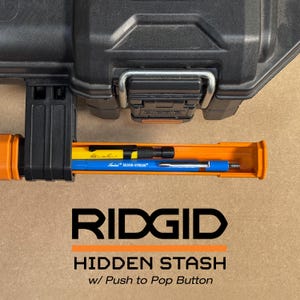 Peut inclure: Mallette &agrave; outils RIDGID noire et orange avec un compartiment cach&eacute; contenant un stylo jaune et bleu. Le texte "RIDGID" et "HIDDEN STASH w/ Push to Pop Button" sont affich&eacute;s en dessous.