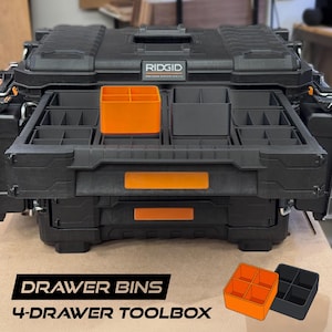 May include: A black Ridgid Pro Gear System 2.0 toolbox with an open drawer containing multiple black and orange plastic storage bins. The bins are square with four internal compartments. The text DRAWER BINS 4-DRAWER TOOLBOX is visible.