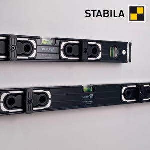 May include: Two black Stabila spirit levels featuring white accents, multiple integrated vials with green liquid, and black adjustable sliding components. The brand name Stabila is printed on the tools along with the text Made in Germany.