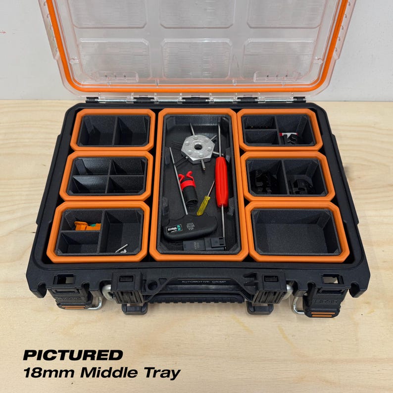 Pu&ograve; includere: Valigetta portautensili nera e arancione aperta con coperchio trasparente, con un vassoio centrale da 18 mm. La valigetta mostra vari strumenti e scomparti. Il testo "PICTURED 18mm Middle Tray" &egrave; visibile in basso.